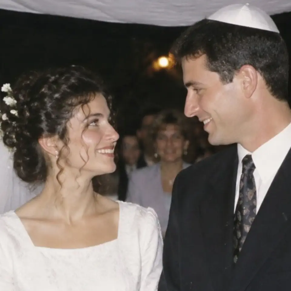 נועה ואורי מתחת לחופה, 1998: הכלה בשמלה לבנה והחתן בכיפה מחייכים זה לזה.